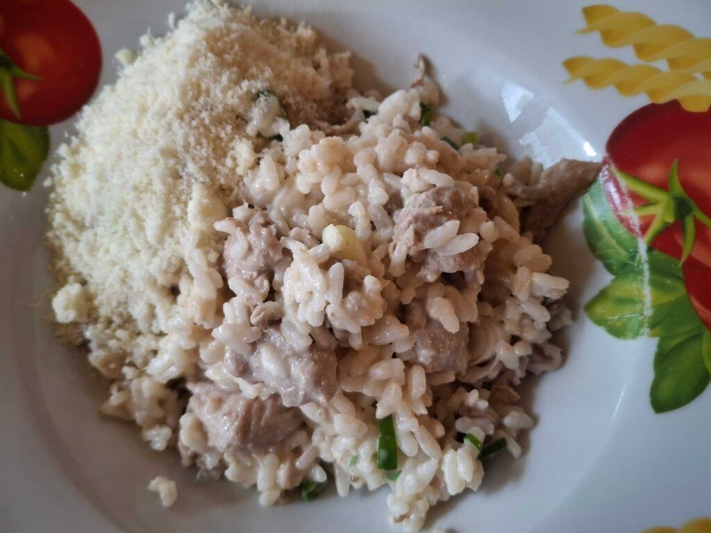 Rizoto připravené z vepřové panenky a hlívy ústřičné posypané nastrouhaným parmezánem